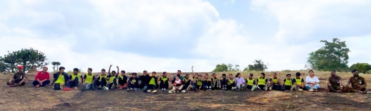 The whole group gathered on the summit rock for a photograph, trees and sky behind them.